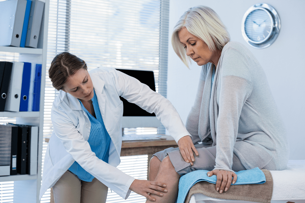 Doktor memeriksa pesakit dengan arthrosis sendi lutut